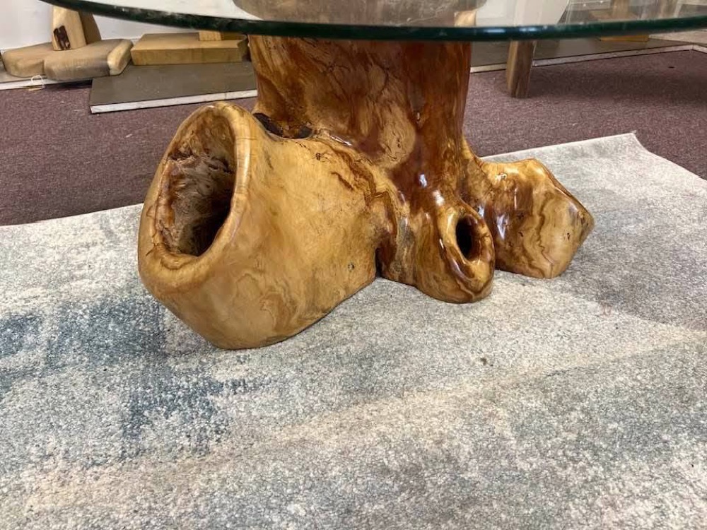 Live-edge table crafted from a tree root with a glass top